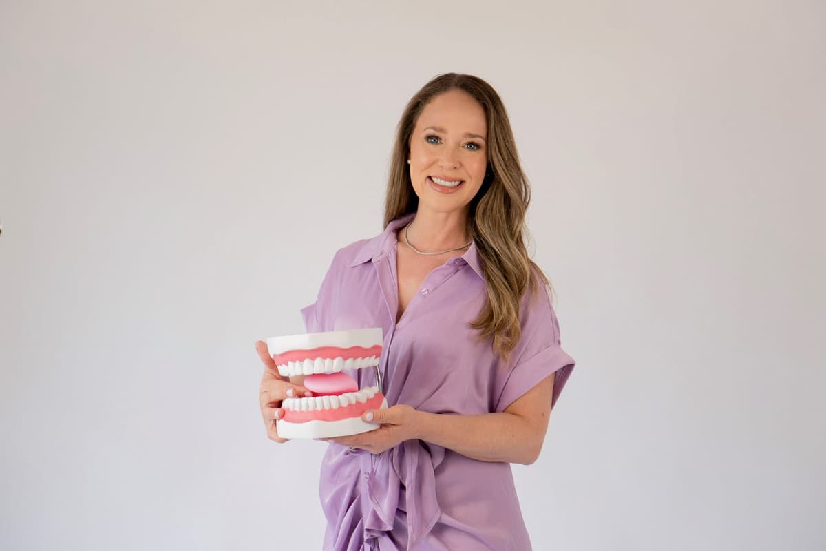 Laura Friedman holding an oversized dental model used to demonstrate proper tongue posture and swallowing patterns in orofacial myofunctional therapy